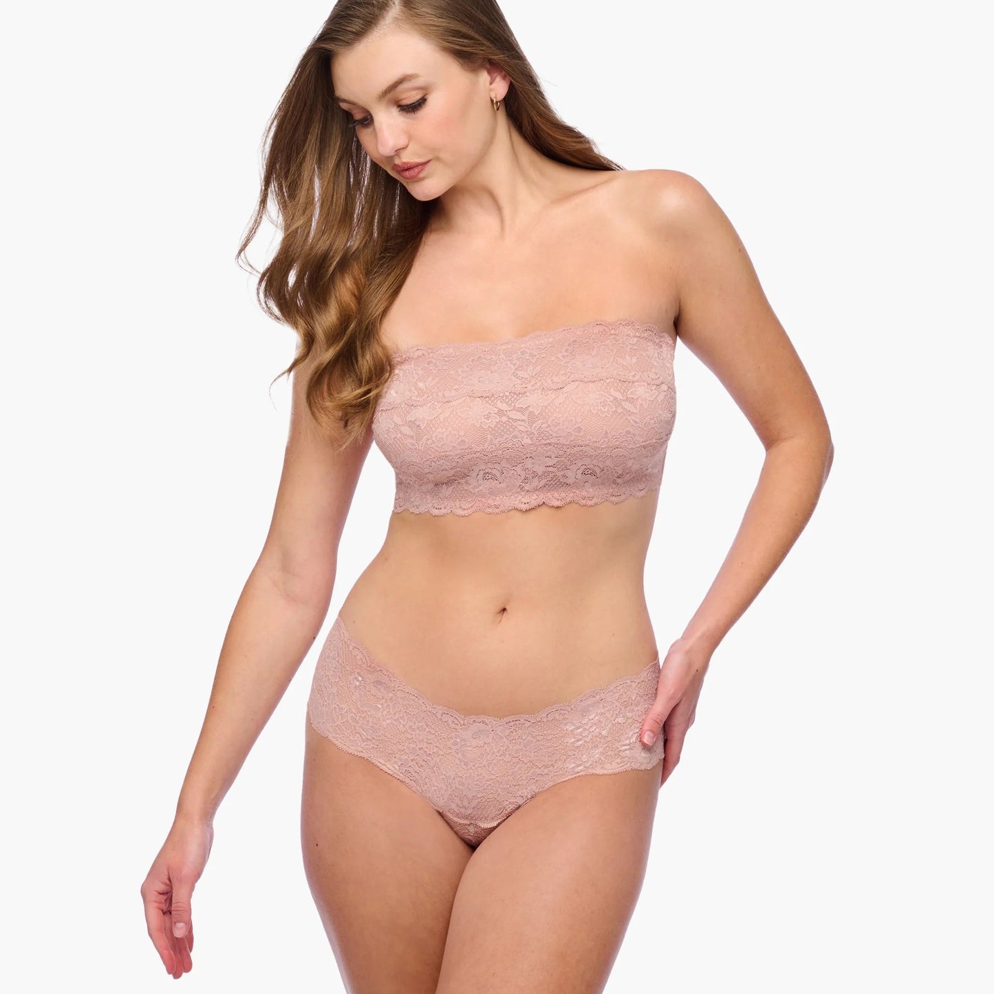 Woman wearing a pink lace strapless top and panties set on a white background