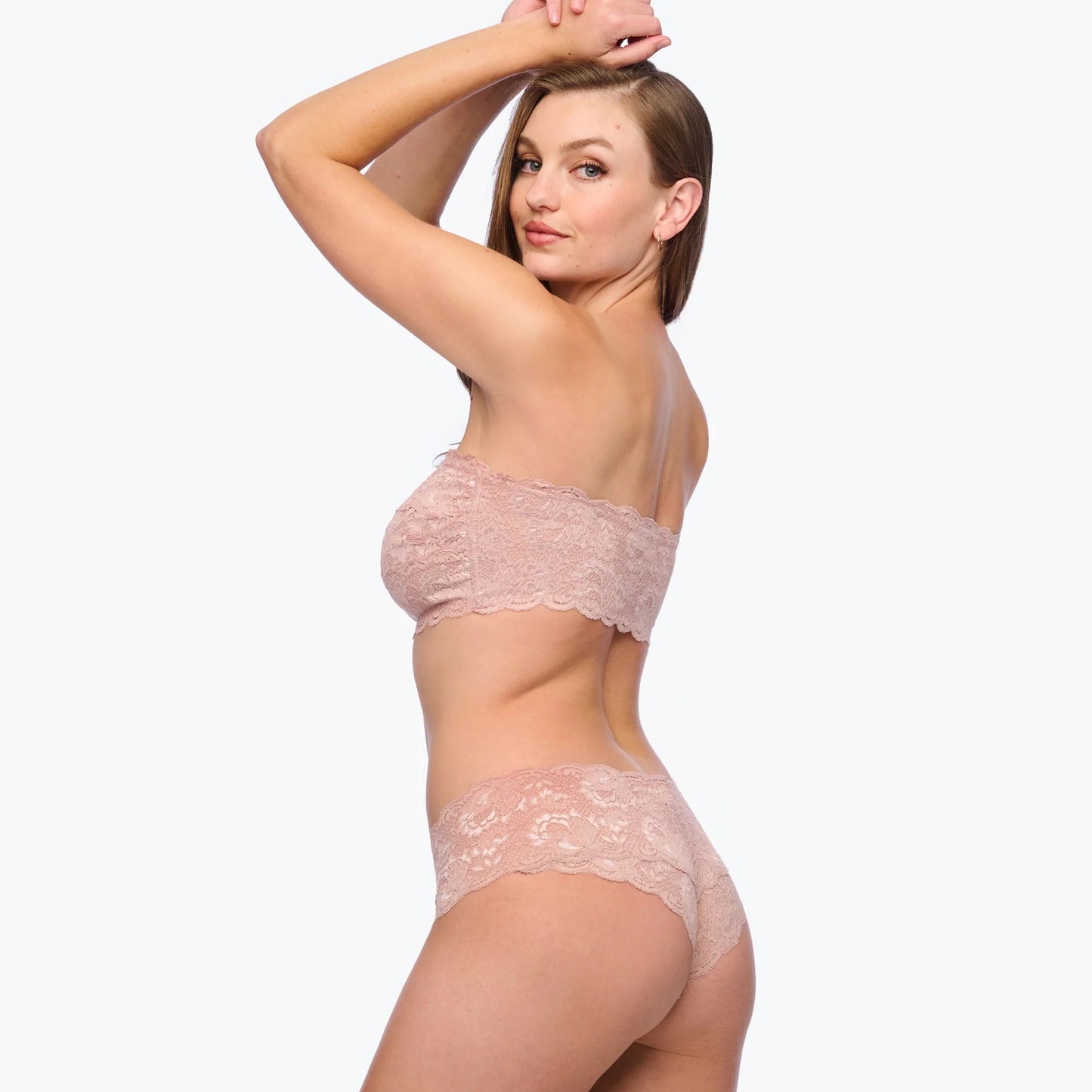 Woman wearing a pink lace lingerie set on a white background