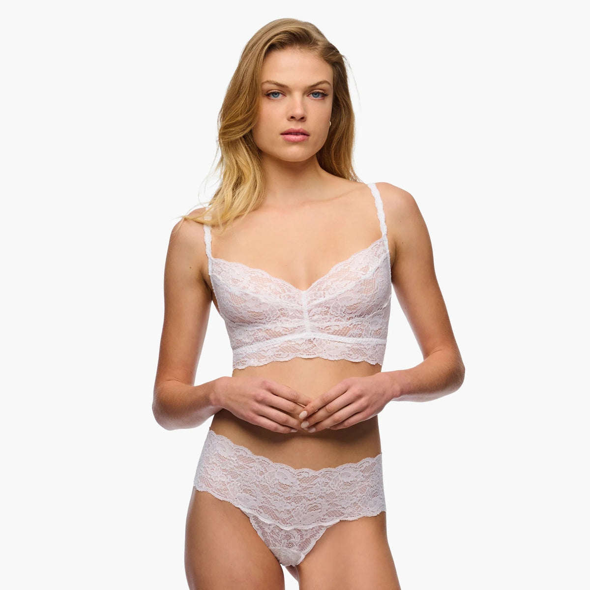 Woman wearing a white lace lingerie set on a white background