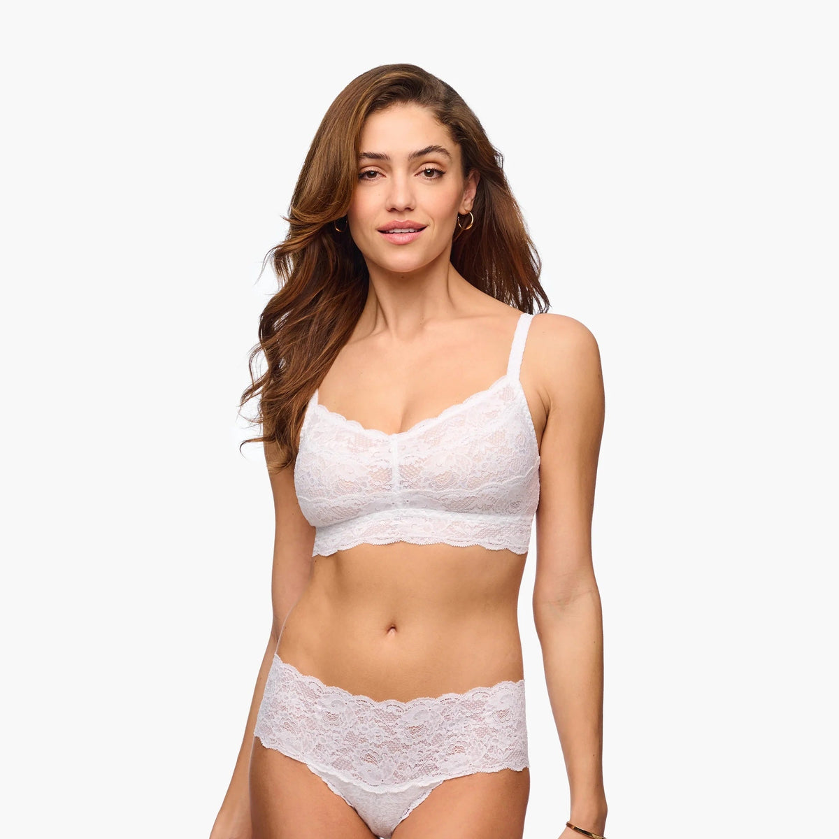 Woman wearing a white lace bra and panties set on a plain background