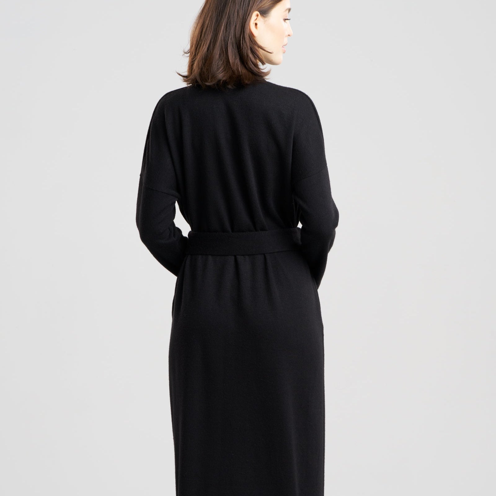 Woman wearing a black dress with a belt on a white background