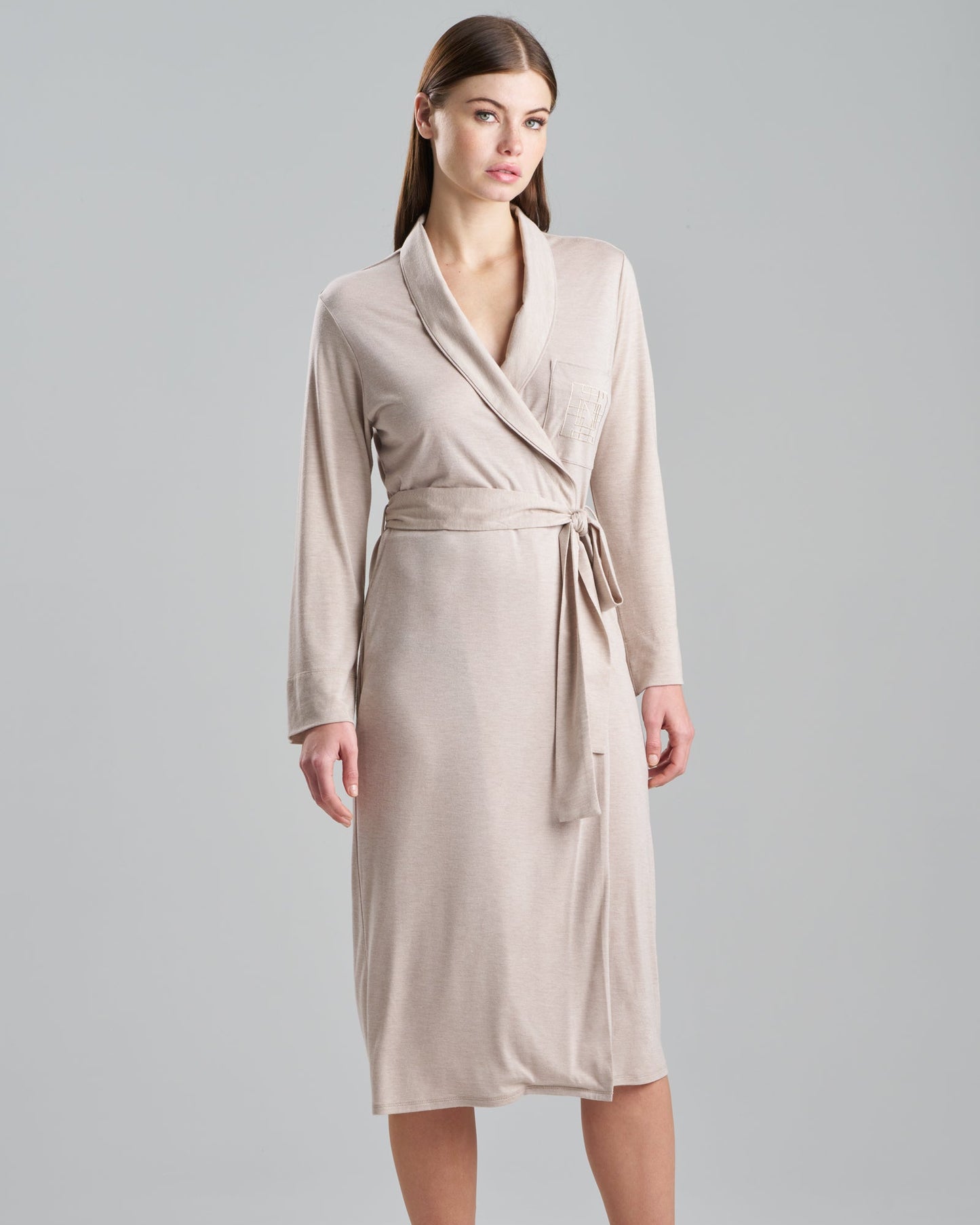 Woman wearing a beige robe against a plain background