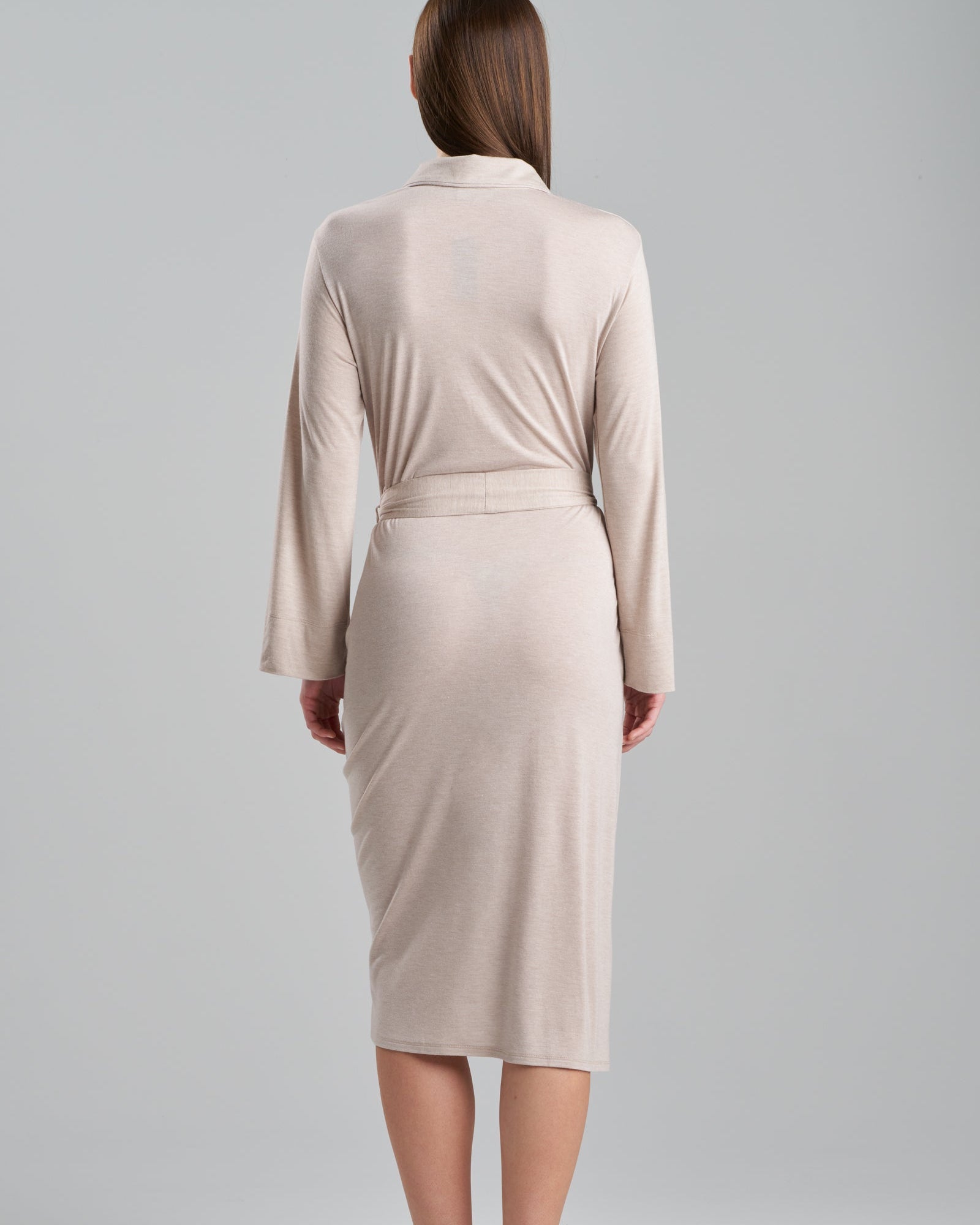 Woman wearing a beige dress with a belt on a gray background