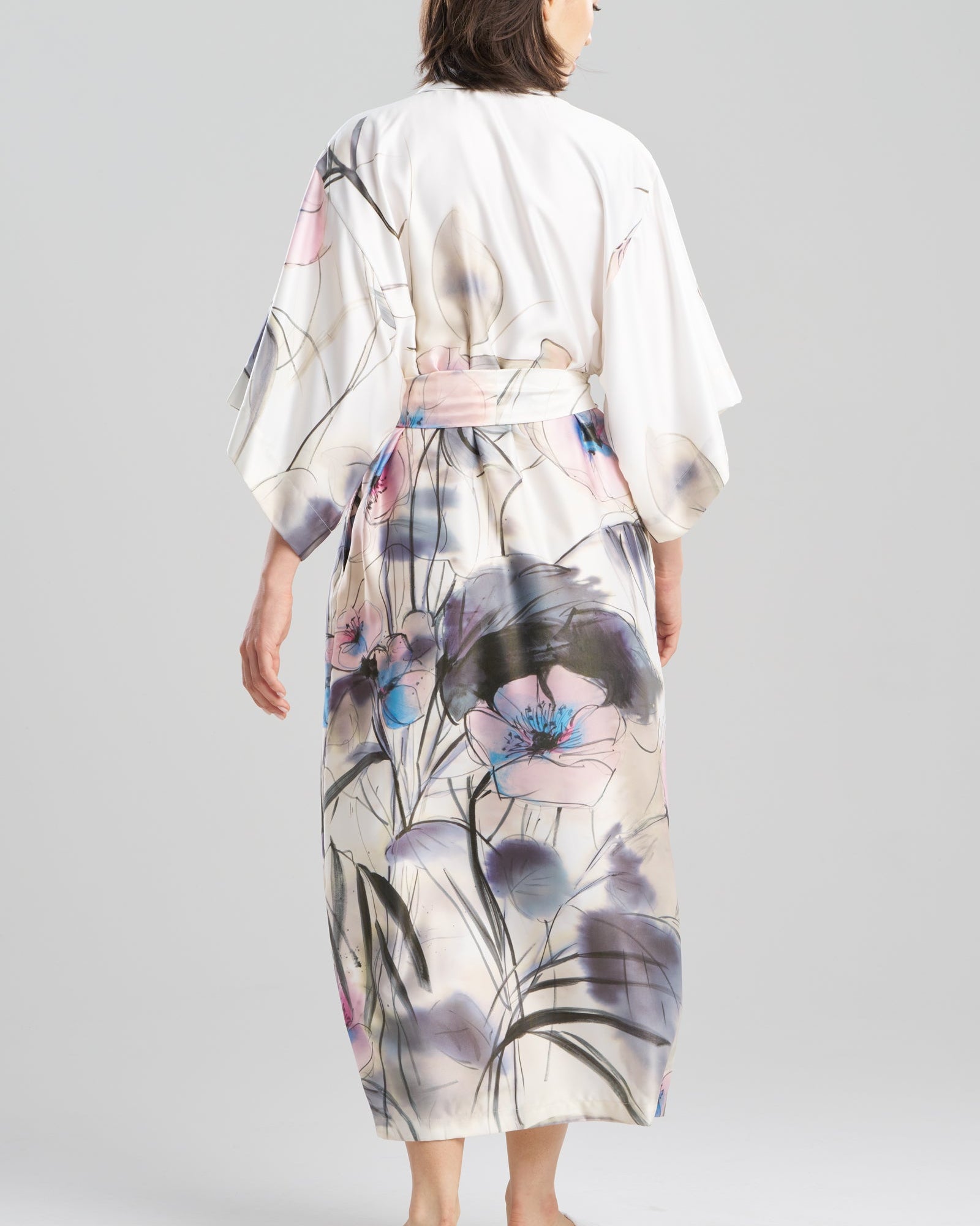 Woman wearing a floral kimono-style garment on a plain background