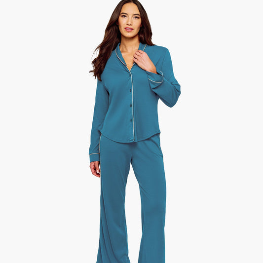 A woman modeling a two-piece pajama set in a teal blue color, featuring a long-sleeve button-up top and matching wide-leg pants, set against a plain white studio background.