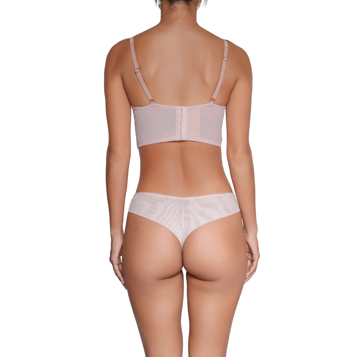 Rear view of a model wearing a light pink sheer mesh bra and matching thong against a plain white background.
