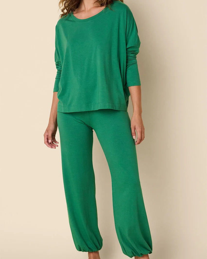 Woman wearing a green pajama set on a beige background