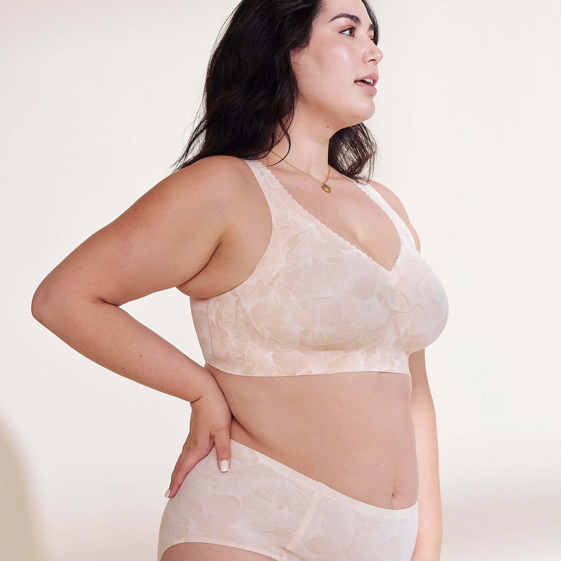 Woman wearing a beige lace bra and panties set on a plain background