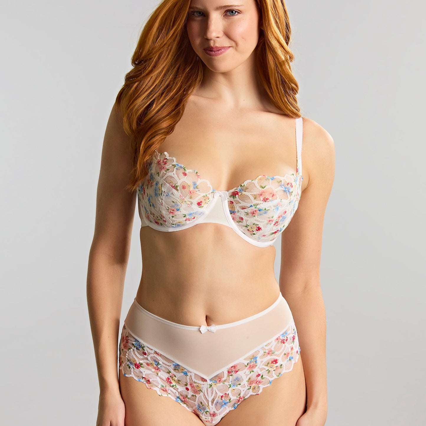 Woman wearing a floral lingerie set against a plain background