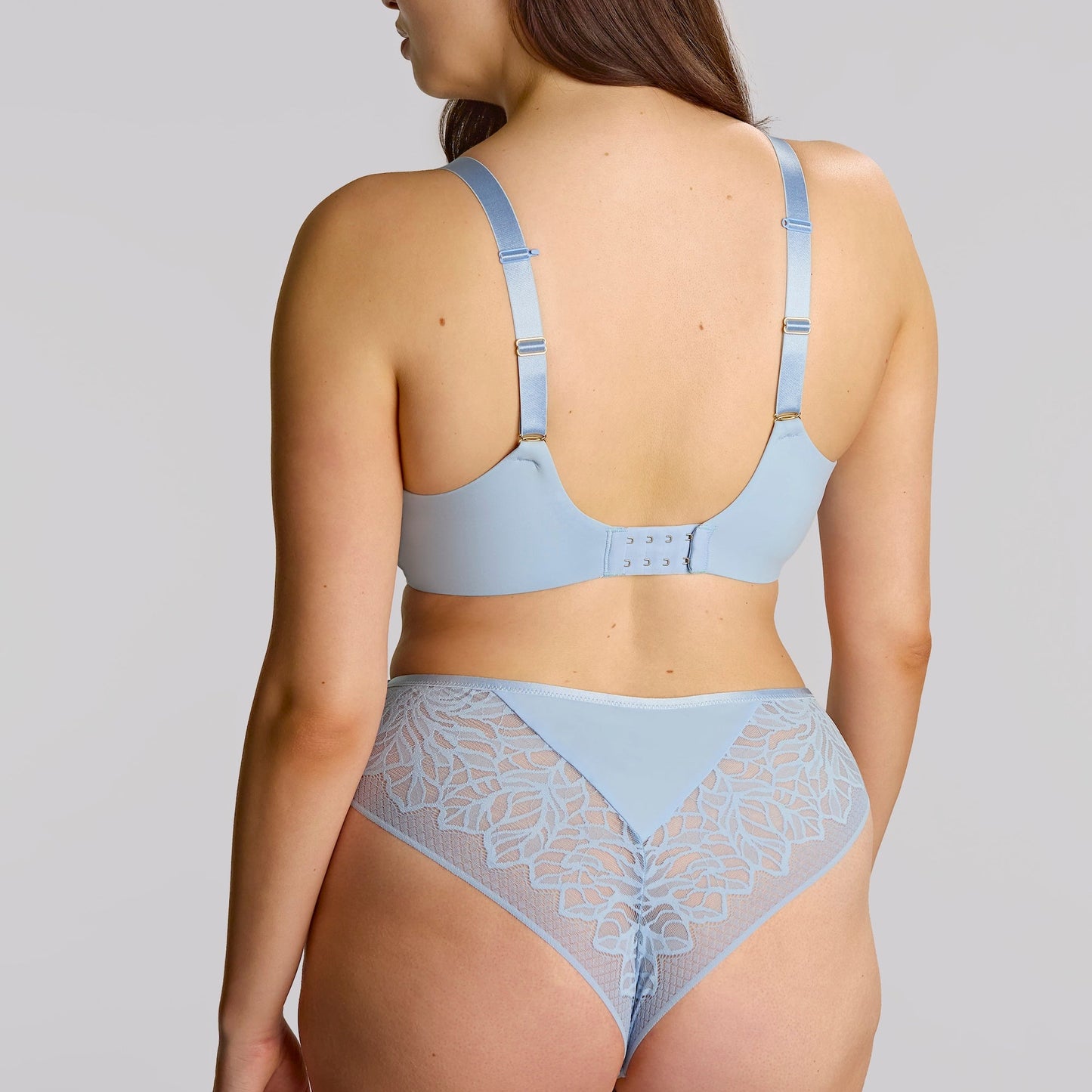 Woman wearing a light blue bra and panties set on a plain background