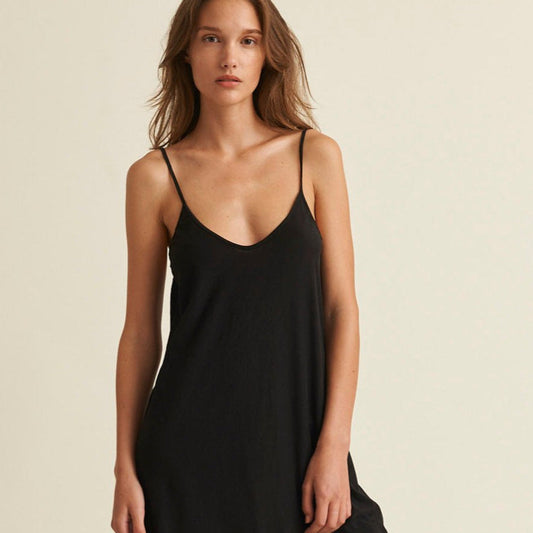 Woman wearing a black slip dress against a beige background