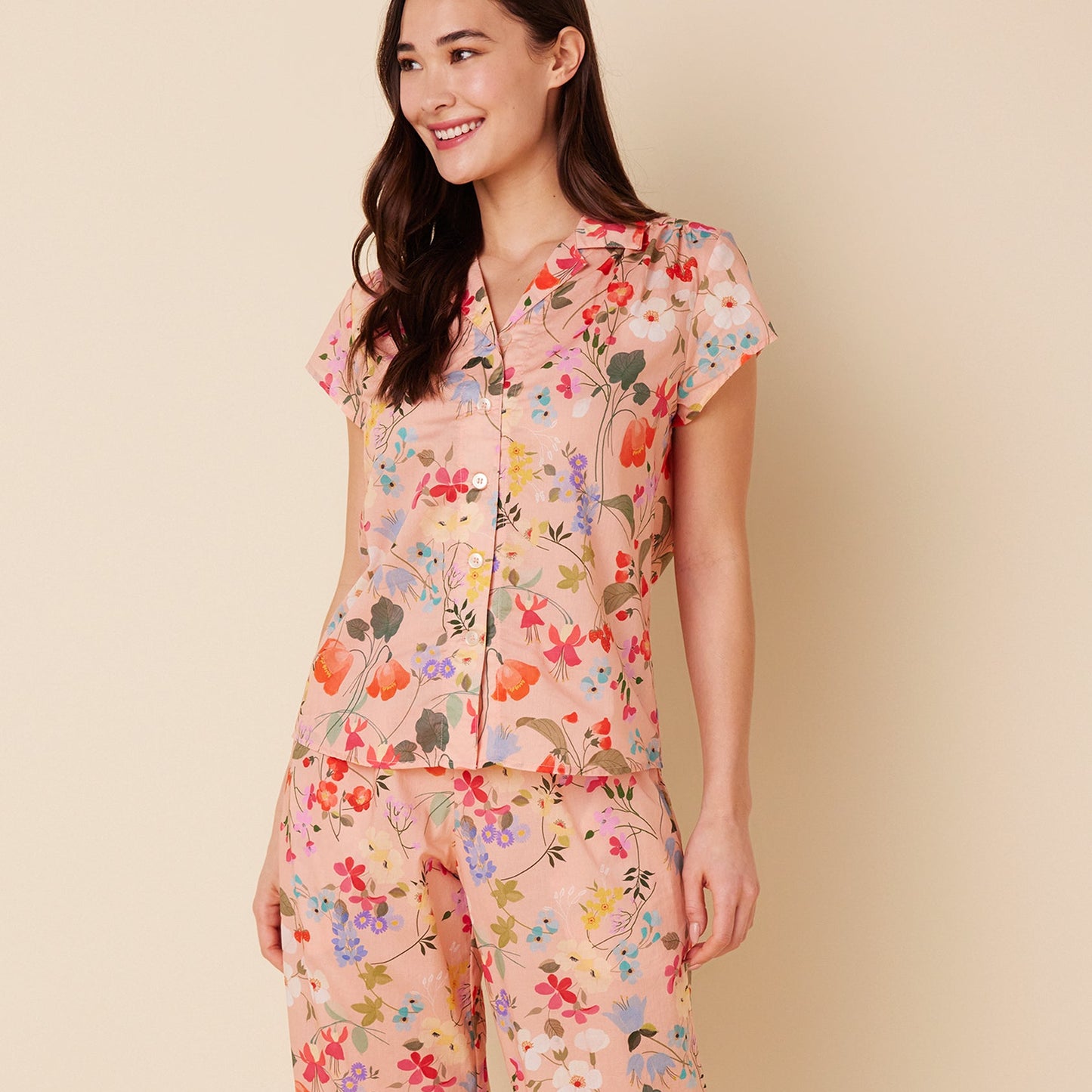 Woman wearing a floral pajama set on a beige background