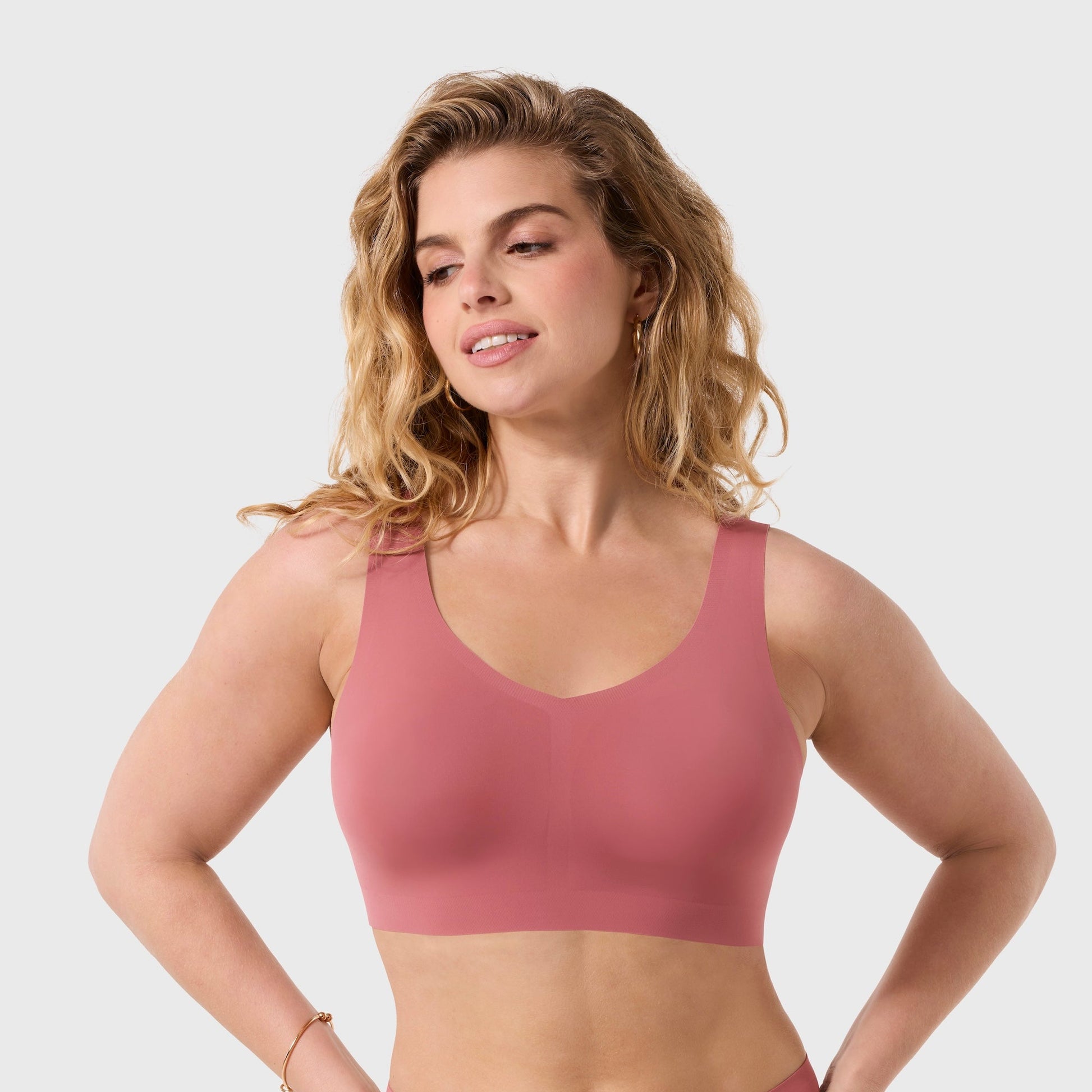 Woman wearing a pink sports bra and high-waisted underwear on a white background