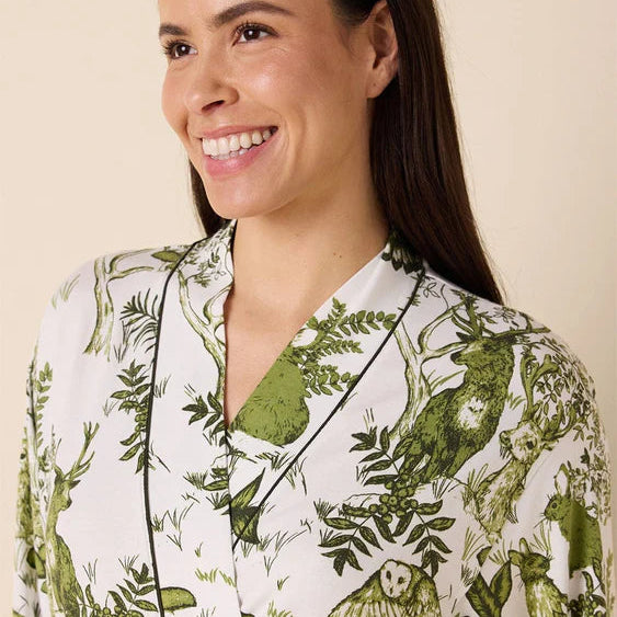Woman wearing a white robe with green floral patterns against a beige background
