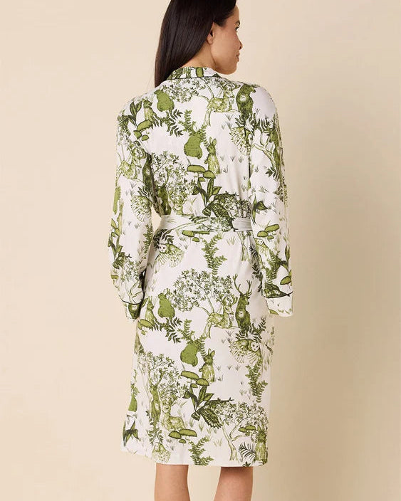 Woman wearing a green and white floral dress against a beige background