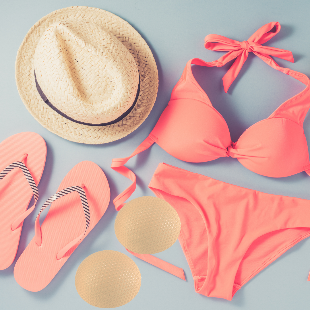 Coral bikini set with pink flip-flops, straw hat, and sun screen on a light blue background