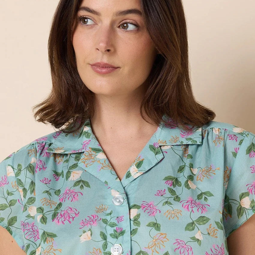 Woman wearing a light blue floral patterned shirt against a beige background